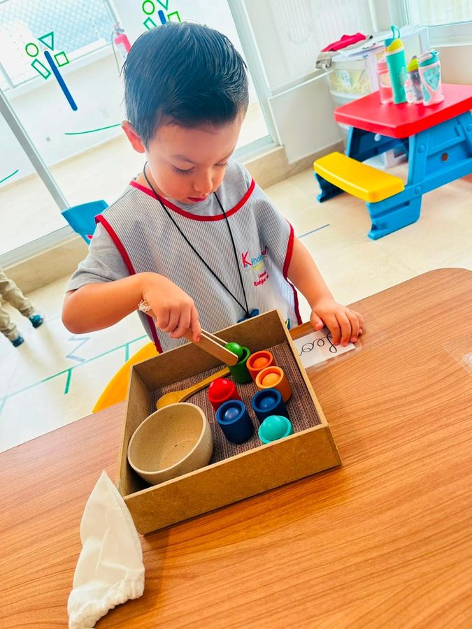 Niño clasificando esferas de colores con pinzas de madera