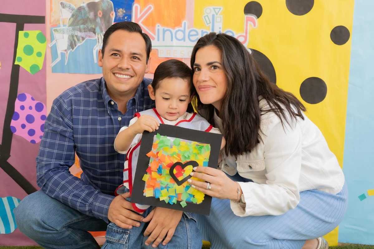 Familia Kinderlied posando feliz con la obra de arte de su hijo en la Feria del Aprendizaje